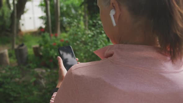 Rear view of senior woman using smartphone in the park