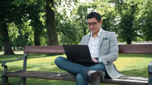 Korean Businessman Working On Laptop In Park