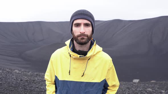 Traveler standing in black cone shaped crater of extinct volcano