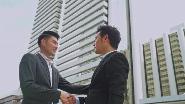 Asian businessmen partnership make handshake after business deal in city building in the background