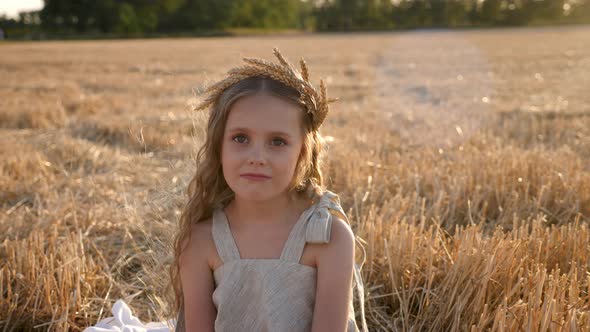 Serious Sad Girl a Child Sit on a Wheat Mown Field