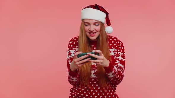 Worried Girl in Christmas Sweater Hat Enthusiastically Playing Racing Video Games on Mobile Phone