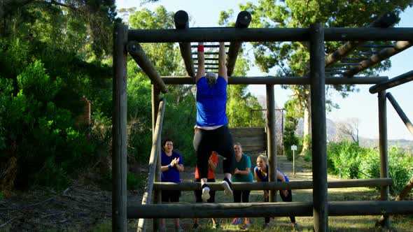 Friends applauding woman while exercising on monkey bar