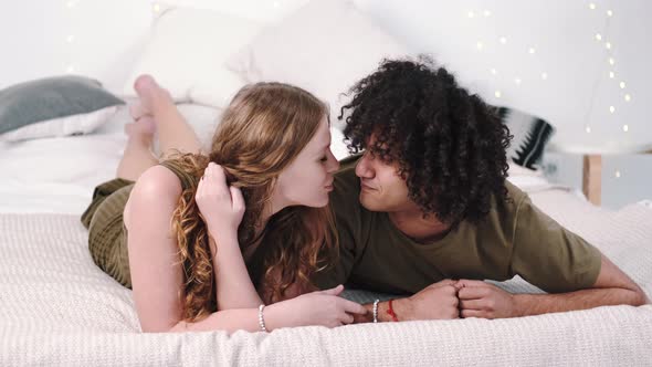 Multiethnic Couplehug and Kiss on White Bed