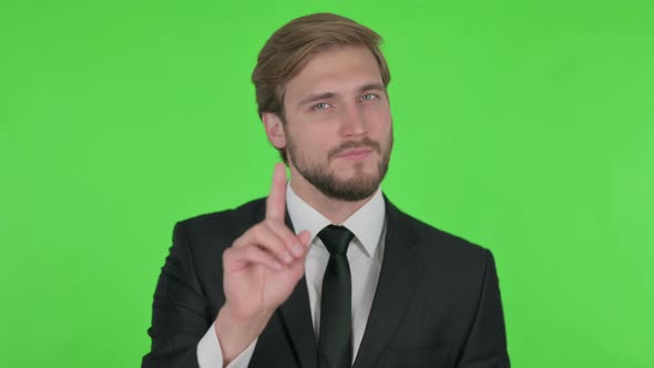 Young Businessman in Denial on Green Background