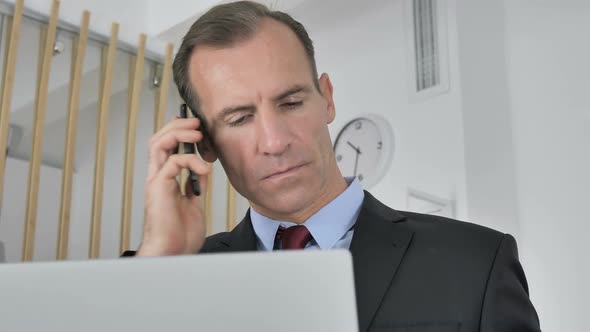 Middle Aged Businessman Talking on Phone Negotiating with Customer