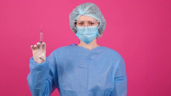 Professional Female Doctor Holds a Syringe with a Vaccine on a Pink Background