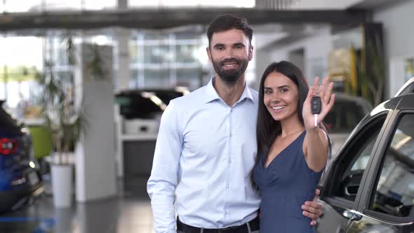 Happy Couple Showing Keys To New Car at Dealership