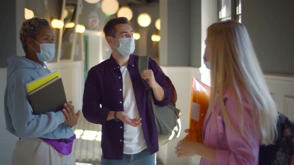 Group of Diverse Students in Facial Mask Chatting Standing in College Corridor on Break