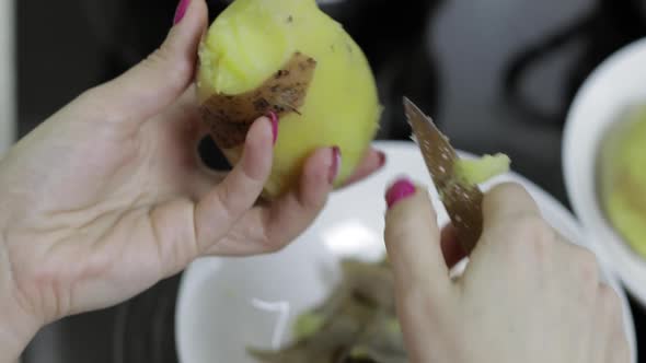 Female Housewife Hands Peeling Potatoes in the Kitchen.