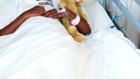 Sick girl in oxygen mask resting with teddy bear