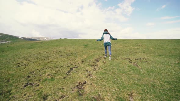 A Young Woman Hiker Running and Spinning on Top of a Mountain