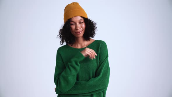 Pretty curly-haired woman wearing hat looking at the camera