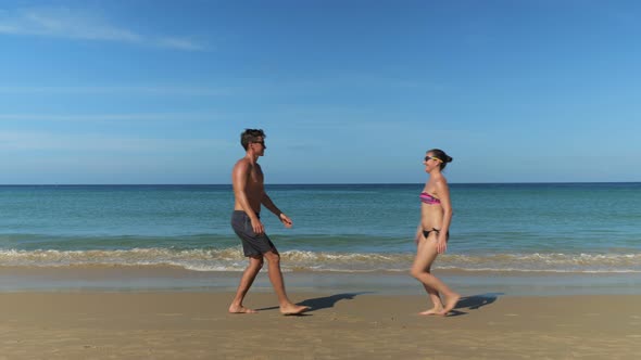 Joyful Young Couple Runs and Hugs on Sunny Beach Near Ocean