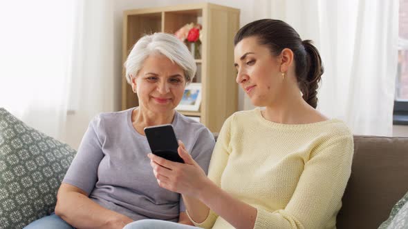 Daughter and Senior Mother with Smartphone at Home