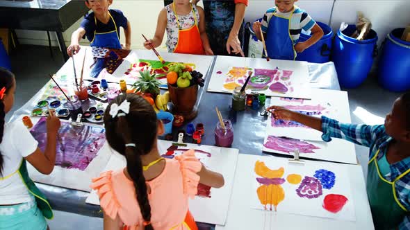 Teacher assisting schoolkid in drawing class