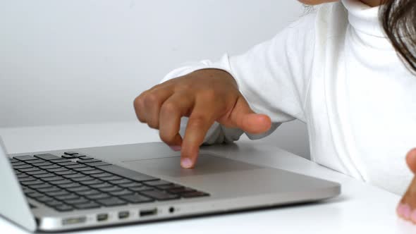 A child girl on distance learning sits in front of a laptop and does homework. Distance learning