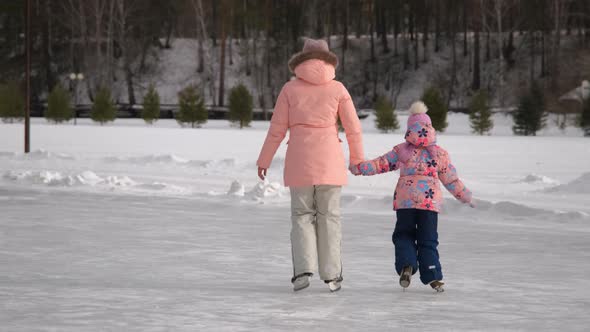 Woman with Little Daughter Figure Skating on Rink