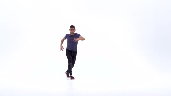 Man Is Dancing Breakdance on the White Background in Simple Grey T-shirt and Grey Jeans. Slow Motion