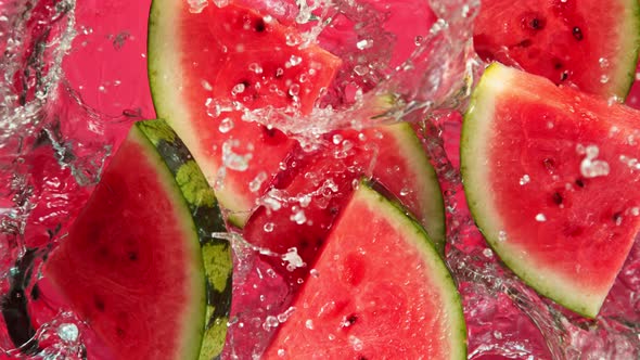 Super Slow Motion Shot of Falling Fresh Watermelon Slices Into Water on Red Background at 1000Fps.