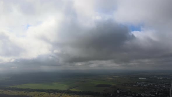 Aerial View From High Altitude of Distant City Covered with Puffy Cumulus Clouds Forming Before