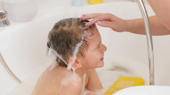 Slow Motion of Young Mother Washing Off Shampoo From Her Little Son Under Shower in Bathroom