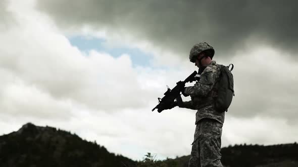 Low shot of soldier firing 40 mm grenade launcher, while standing.