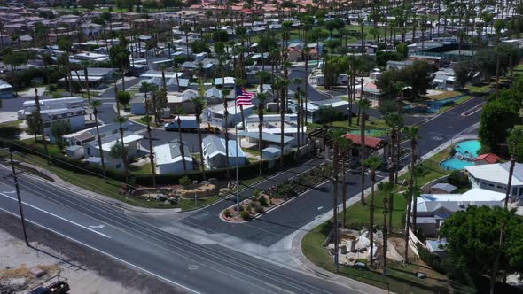 Flight above empty expressway by American flag and community of residential homes on flat plains wit