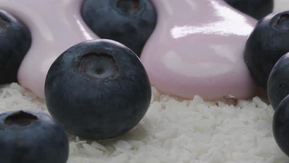 Icing Sugar Flows between Blueberries Lying on Coconut Flakes.