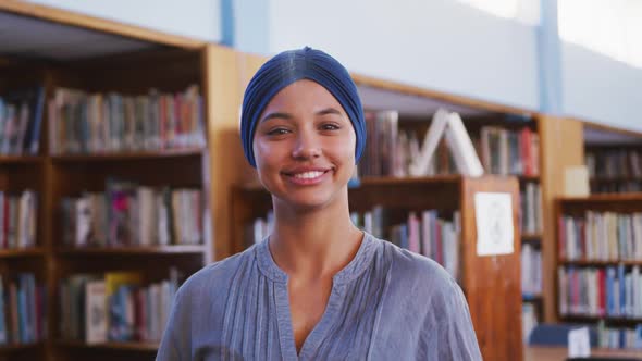 Asian female student wearing a blue hijab looking at camera and smiling