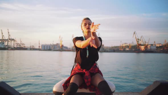 Young Stylish Funky Girl with Green Hair Riding Roller Skates and Dancing Near Sea Port During