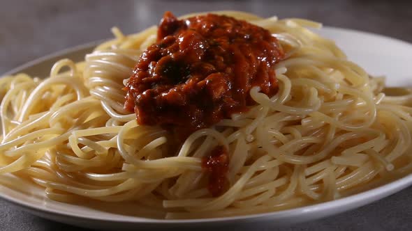 Pouring tomato with tuna sauce over boiled spaghetti