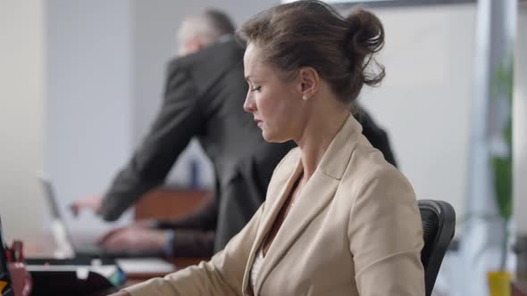 Side View Portrait of Busy Focused Confident Woman Working in Office with Blurred Colleagues at