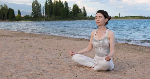 Woman practicing yoga outside in lotus pose on beach