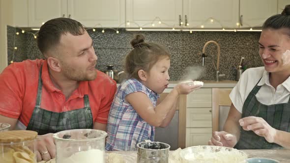 Dad, Mom and Little Daughter Are Cooking Something in the Kitchen. Everything Turns Into a Fun Game.