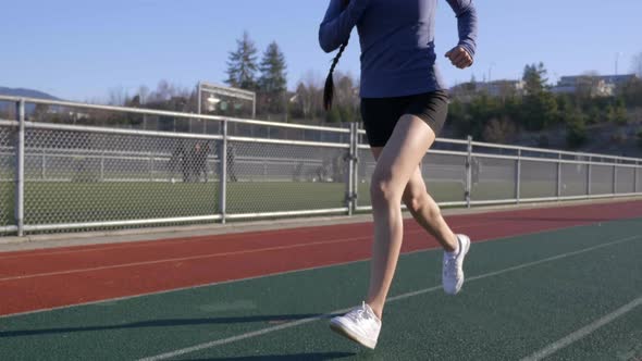 Sporty Hispanic Woman Running on Track, Tilt Up from Feet to Face