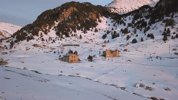 Smooth drone traveling through the snowy town of Cortals in Andorra, with the last lights of the day