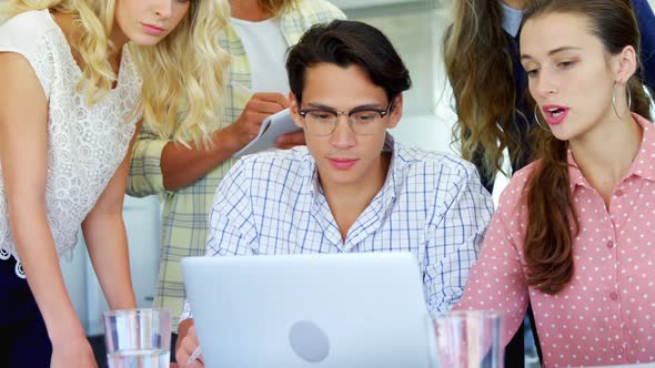 Colleagues discussing over laptop at table