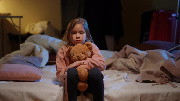 Portrait of Stressed Scared Ukrainian Girl Hugging Teddy Bear Looking at Camera Sitting in Bomb