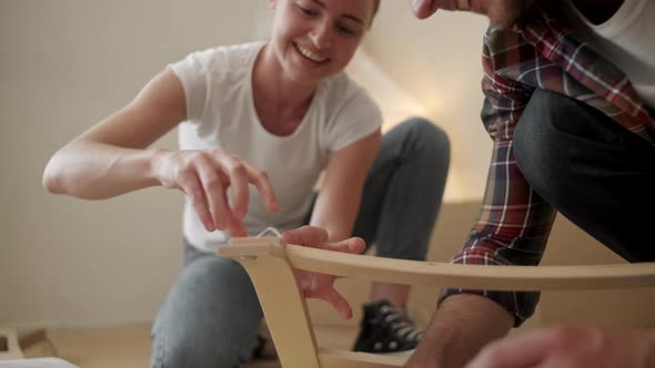 Young Adults Moving in New Home. Couple Moving in Assembling Chair Furniture. Young Interracial