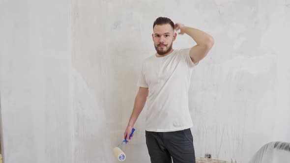 a Young Man with a Funny Mustache Straightens His Fashionable Hairstyle and Holds a Wall Paint