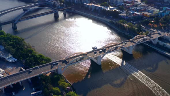Ferry Boat Cruising in The Brisbane River Passing Under William Jolly Bridge With Traffic At Dusk In