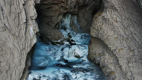 The Stream of the Mountain River in a Narrow Gorge Covered with Ice