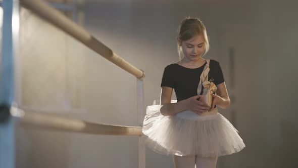 Beautiful Thoughtful Caucasian Girl in Tutu Standing with Pointes in Backlit Fog Looking at Camera