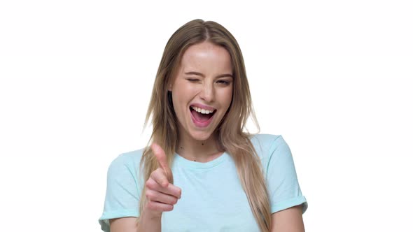 Portrait of Joyous Blonde Woman 20s in Casual Clothing Smiling and Pointing Finger on you Meaning
