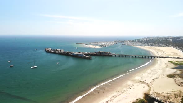 Aerial shot over Stearn's Wharf pier and the clear blue ocean harbor full of sail boats in Santa Bar