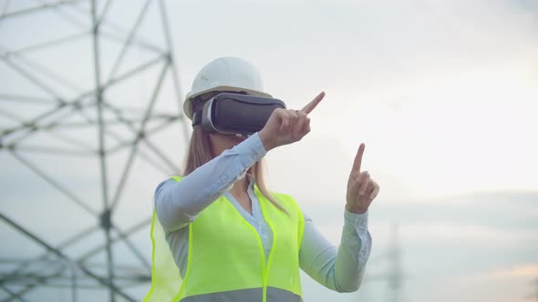 Middle Plan Female Energy Engineer in Virtual Reality Glasses and White Helmet on the Background of