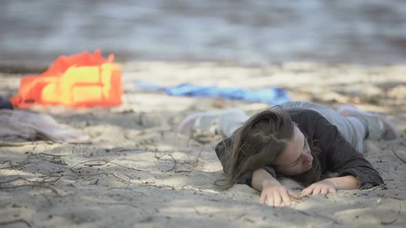 Exhausted Woman Lying on Beach, Looking With Plea for Help, Crash Survivor