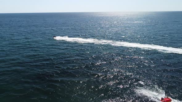 Happy People Swim on Air Mattress Behind a High Speed Water Bike