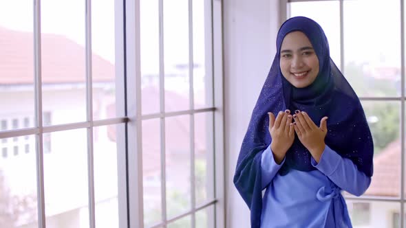 Asian Muslim young woman in traditional hijab is praying glorify Allah